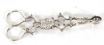 A pair of antique Irish silver sugar tongs, circa 1780 of Rococo scrolled form, the circular hinge