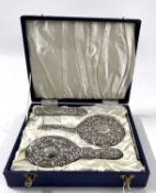 Cased three piece silver backed dressing table set comprising hand mirror, hairbrush and clothes