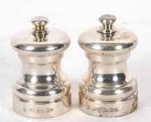 A pair of Elizabeth II silver salt and pepper grinders, plain rounded baluster bodies with metal and