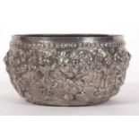 An Indian white metal bowl circa 1915 decorated with images of deities between an arbor of
