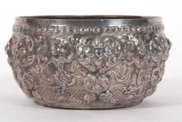 An Indian white metal bowl circa 1915 decorated with images of deities between an arbor of