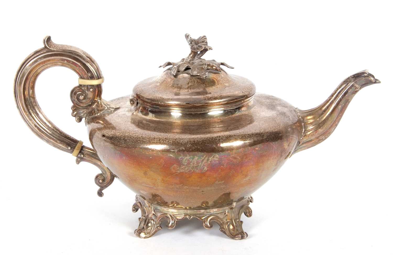 A William IV silver teapot of compressed circular plain form having a cast floral and leaf finial,