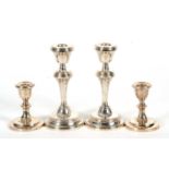 A pair of Elizabeth II silver candlesticks having tapering stems and reeded detail, loaded bases,