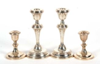 A pair of Elizabeth II silver candlesticks having tapering stems and reeded detail, loaded bases,