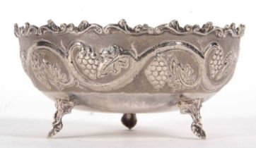 A vintage white metal 830-Cyprus bowl decorated with a vine and grape design and supported on