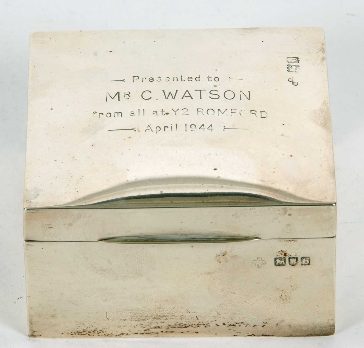 A late Victorian silver table cigarette box of square form, the lid with presentation engraving,