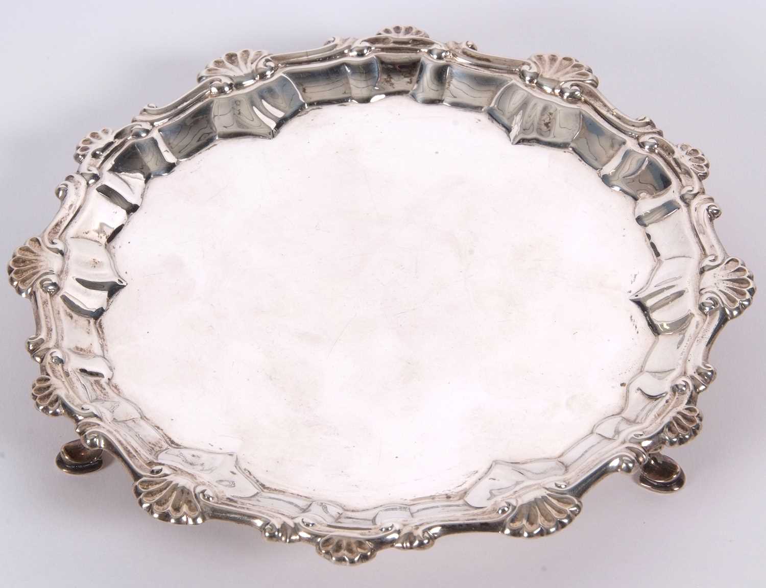 A George III silver waiter or small salver having a pie crust rim with shell motifs, supported on - Image 2 of 4