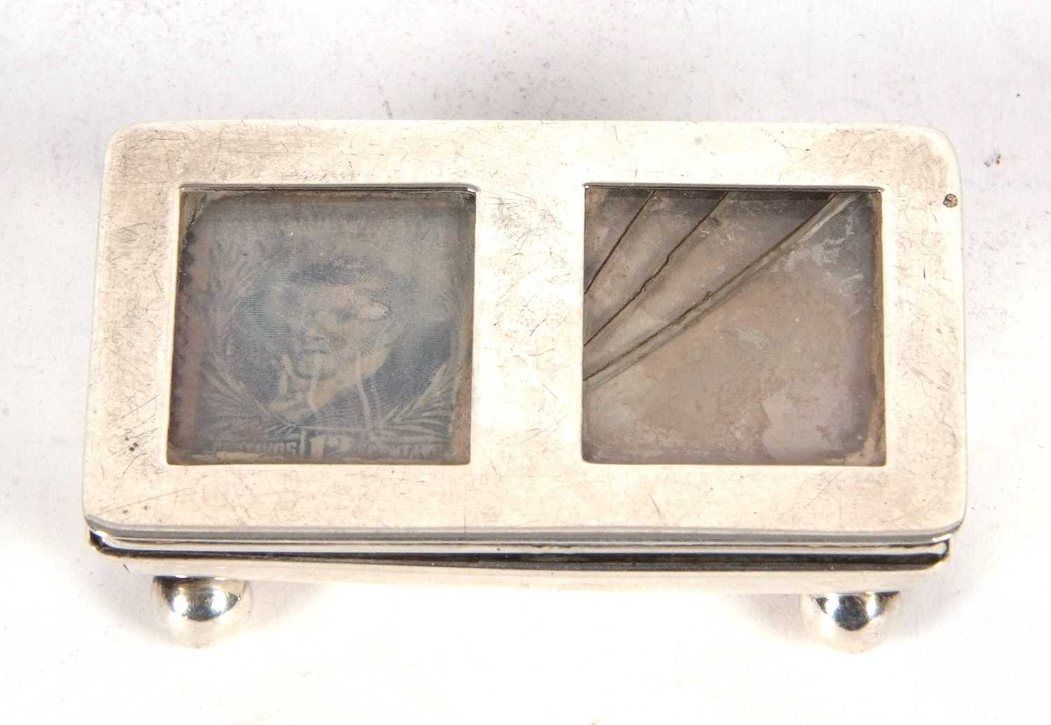 An antique silver double stamp box of trough shape with sprung glazed hinge lid standing on four