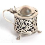 An Edwardian silver pierced drum mustard, the hinged lid with a slight domed plain design, shell