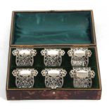 Cased set of six Edwardian silver serviette rings, the fronts pierced around a vacant oval shaped