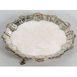 A George III silver waiter or small salver having a pie crust rim with shell motifs, supported on