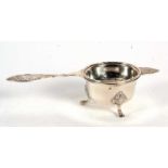 A hallmarked silver tea strainer and bowl, the tea strainer with pierced bowl and applied wavey