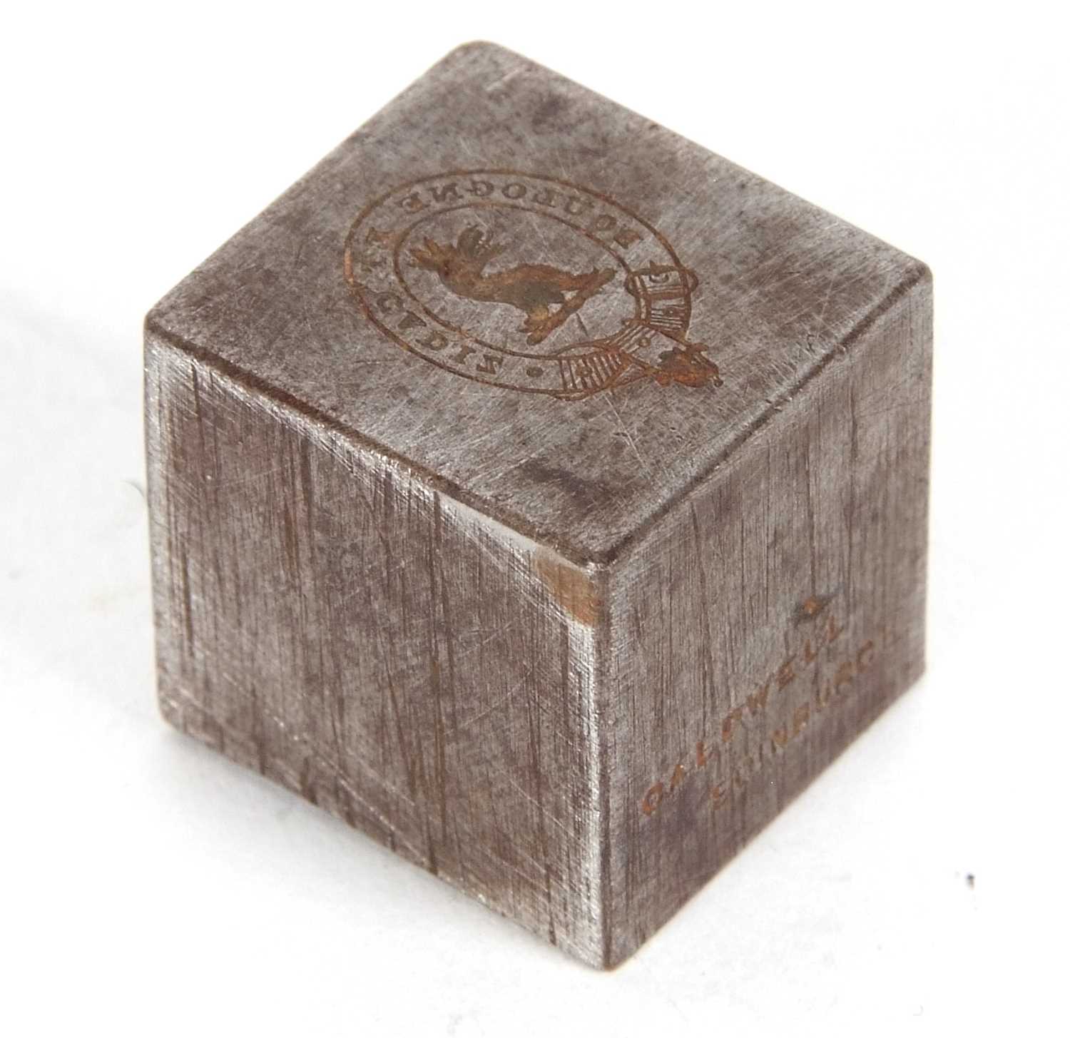 A vintage metal cube shaped paperweight/seal, one side engraved with a griffin head within a Latin