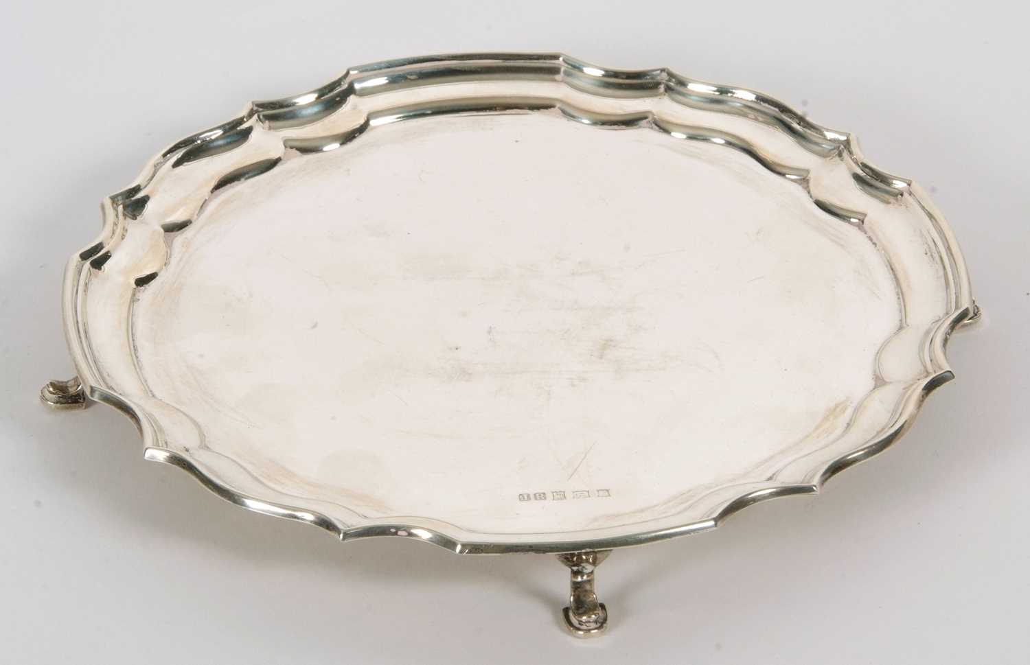 An Elizabeth II silver card salver in Georgian style of circular form with a Chippendale style