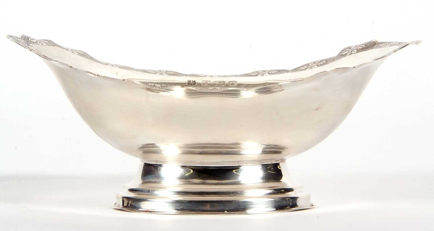 An Elizabeth II silver small pedestal dish of oval form having a shaped border, chased and