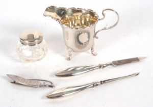 Mixed Lot: A small George V silver cream jug having a castellated rim, scroll handle and supported
