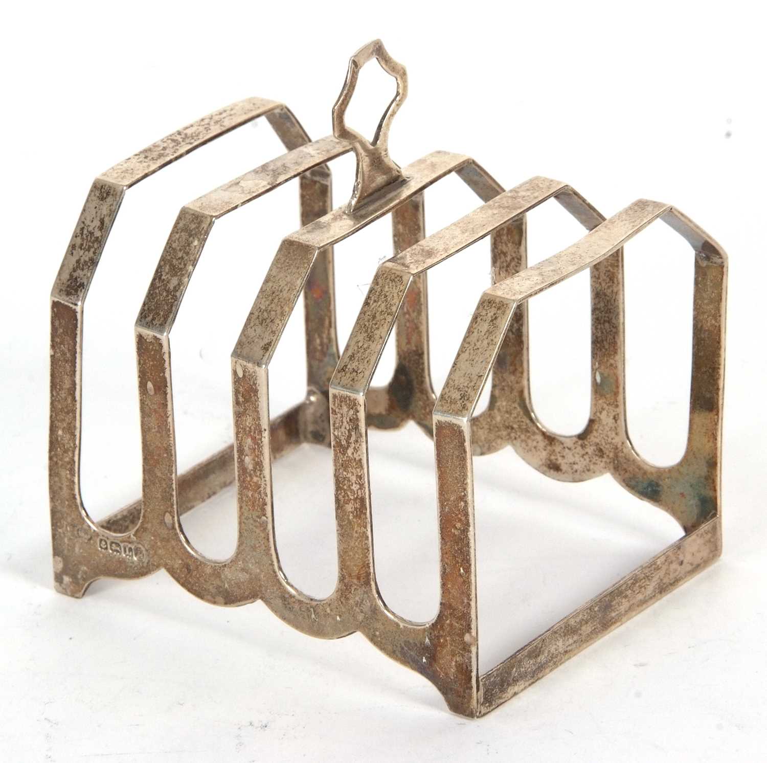 An Art Deco silver toast rack of angular form, four divisions with central loop carrying handle,