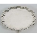 A sterling silver card salver of plain form, having pie crust edge and supported on three cast