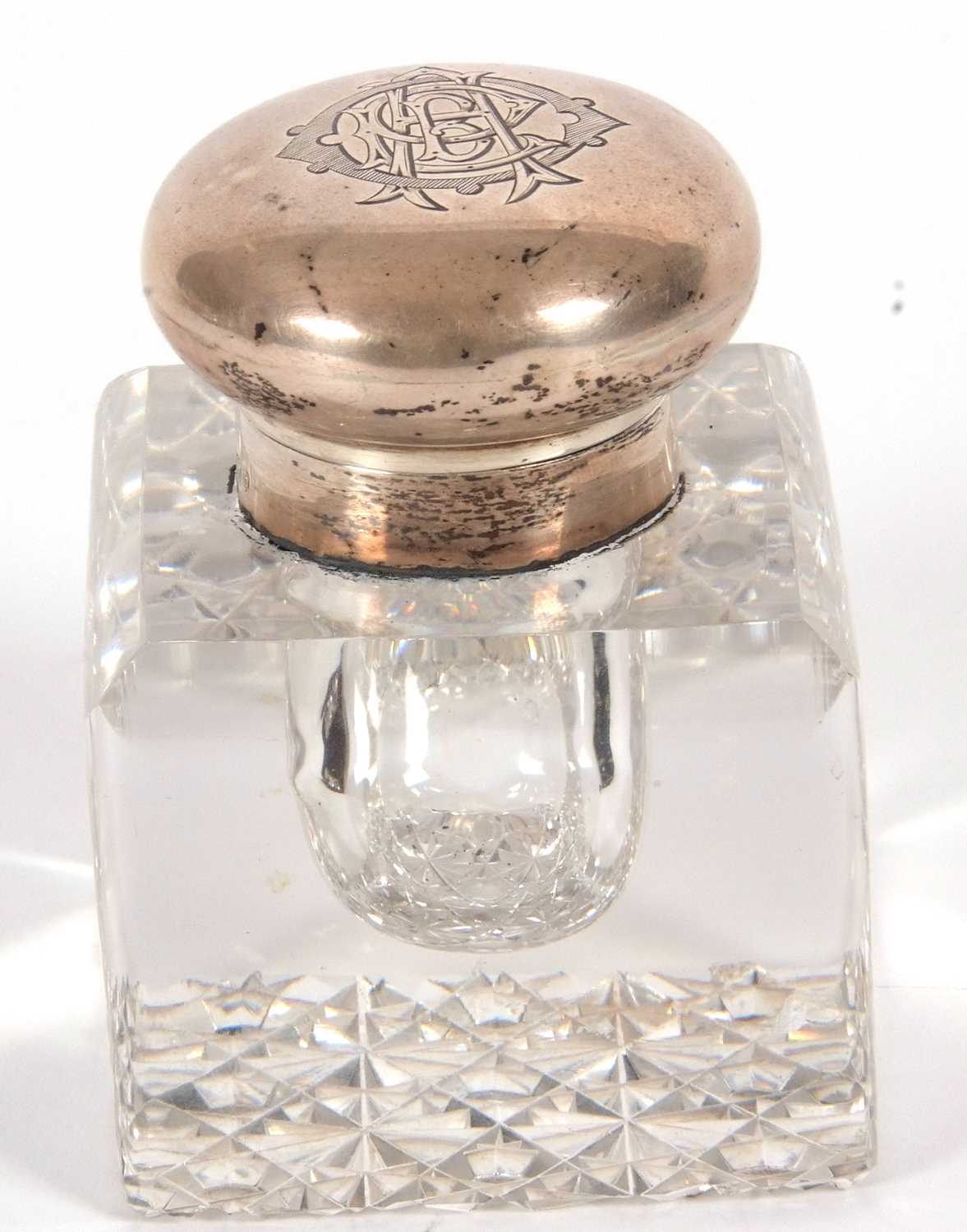 An early 20th Century glass and silver mounted inkwell of square form with chamfered edges and a
