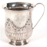 A George III silver mug of slight baluster shape having a reeded handle, garland and fluted