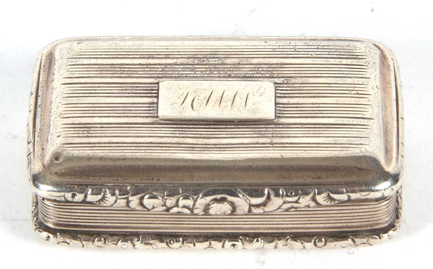 A George IV silver snuff box of rectangular form having cast foliate edges and thumb piece, engraved