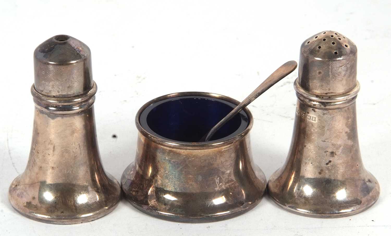 A Elizabeth II silver three piece condiment set comprising salt, pepper, mustard and liner,