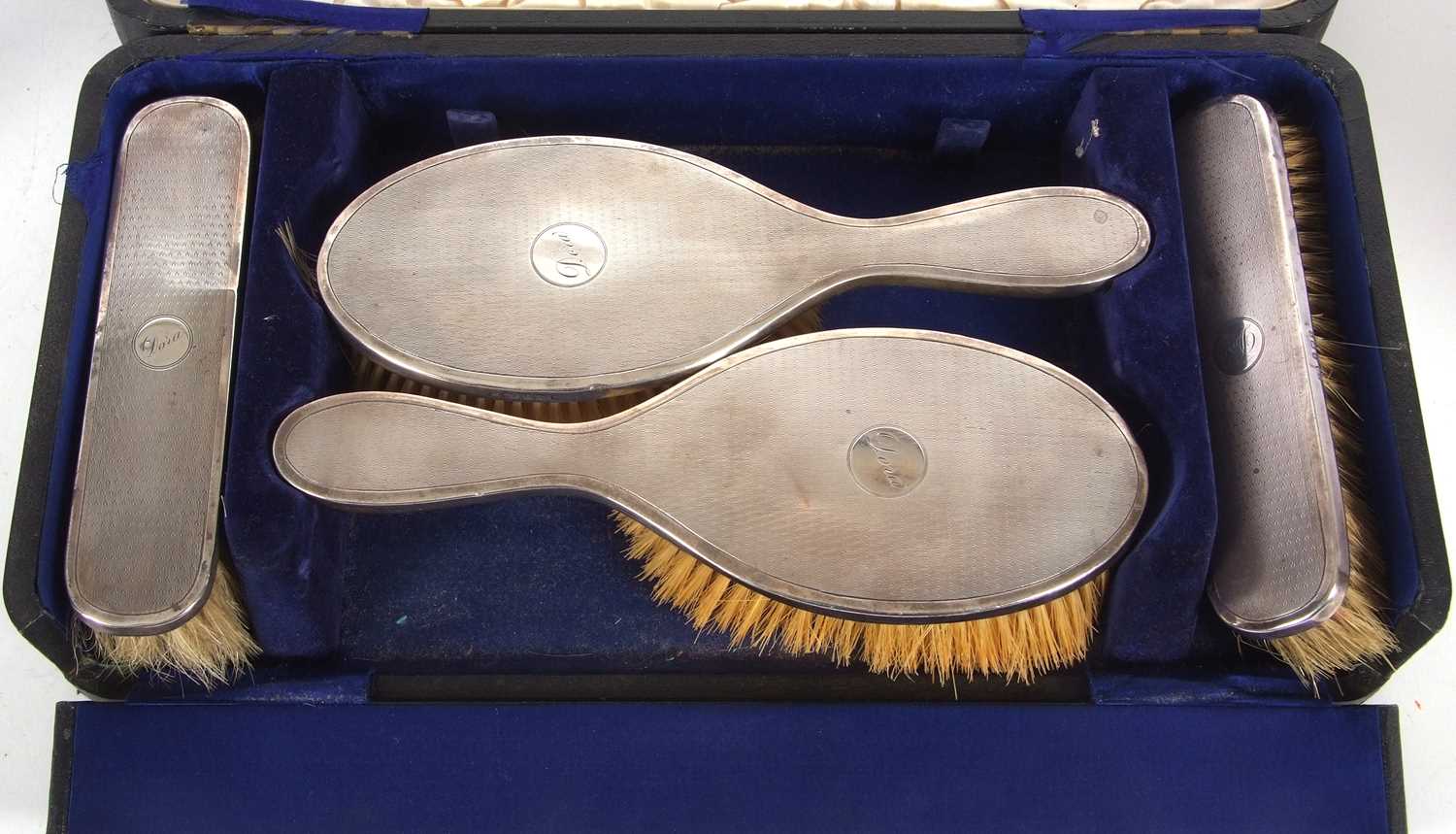 A cased George V silver backed dressing table set comprising hand mirror, two clothes brushes, two - Image 2 of 4