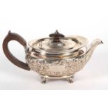 A George III silver teapot of oval form and elaborately decorated with scrolled flowers,