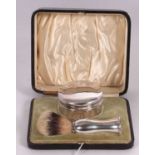 A late Victorian cased shaving silver handled brush and silver lidded pomade jar, both engraved with