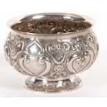 A late Victorian silver pedestal bowl of squat circular form, elaborately embossed all over with