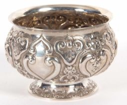 A late Victorian silver pedestal bowl of squat circular form, elaborately embossed all over with