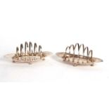 A pair of Edwardian silver toast racks, boat shaped, each with six graduated dividers, supported