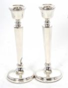 A pair of silver hallmarked candlesticks having urn shaped sconces, hexagonal shaped tapering