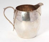 A George V silver cream jug of bulbous circular form having sparrow beak spount, scrolling C