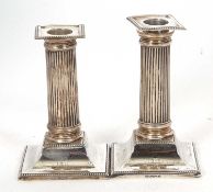 A pair of small Edwardian candlesticks having beaded rims, fluted columns and detachable sconces