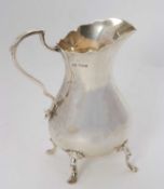 An Edwardian large silver cream jug of plain round bellied form having a wavey rim, scrolled handle,