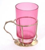 An Art Deco silver glass holder of plain circular form having an angular handle joined by a strap