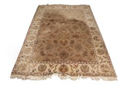 A 20th Century wool floor rug decorated with a stylised floral design on a cream and taupe