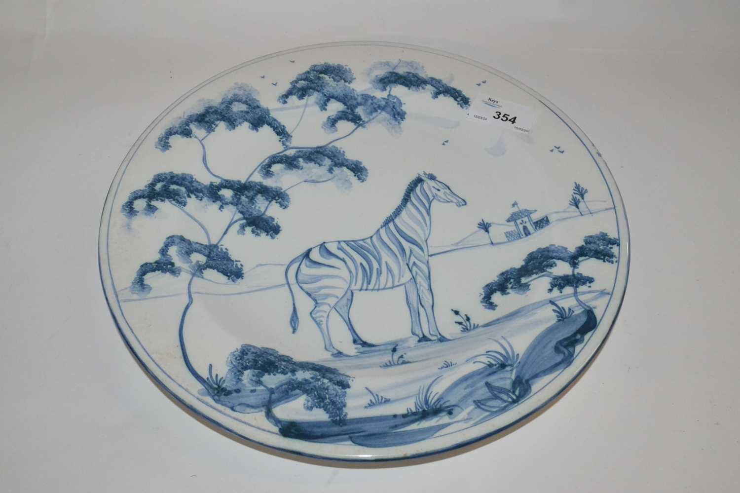 A Isis Ceramics dish made for Colefax & Fowler decorated in Delft style with a giraffe in a