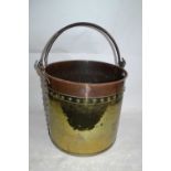 A large brass and copper coal bucket with looped iron handle, 40cm high, 42cm diameter