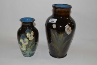 A pottery vase with an impasto type design of flowers together with a similar vase, largest 27cm