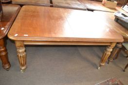 A Victorian mahogany extending dining table raised on fluted legs with casters, lacking extension