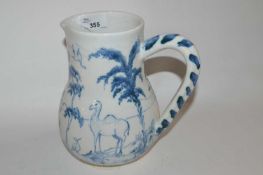 A Isis Ceramics type jug decorated with a camel and a monkey in Delft style, slightly crazed,