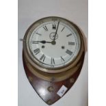 Ships brass bulkhead clock of typical form with a unsigned 7" dial, set on a hardwood backing