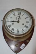Ships brass bulkhead clock of typical form with a unsigned 7" dial, set on a hardwood backing