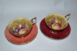 A pair of Aynsley cups and saucers decorated with fruit, signed by Jones