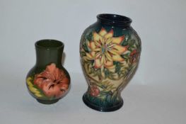 A small Moorcroft vase decorated with Hibiscus on a green ground together with a further Moorcroft