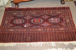 A Belouch wool wall hanging decorated with geometric patterns in red, blue and cream, 137cm wide (