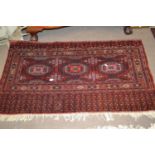 A Belouch wool wall hanging decorated with geometric patterns in red, blue and cream, 137cm wide (