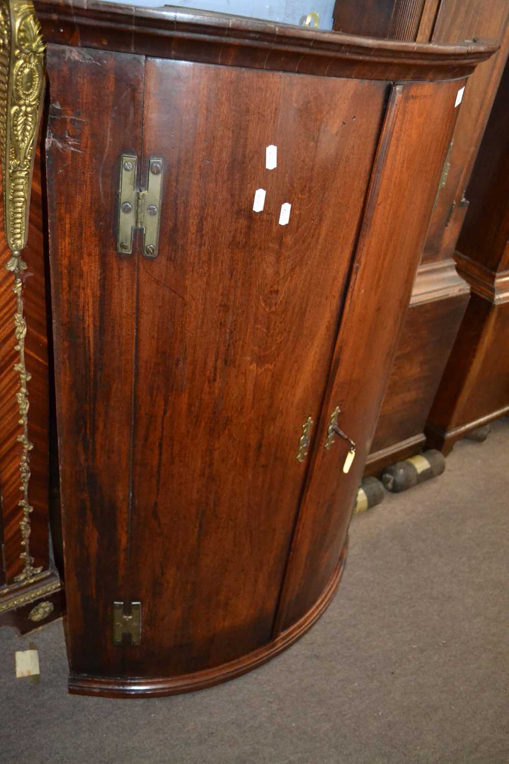 A George III mahogany bow front two door wall mounted corner cabinet with shelved interior, 110cm